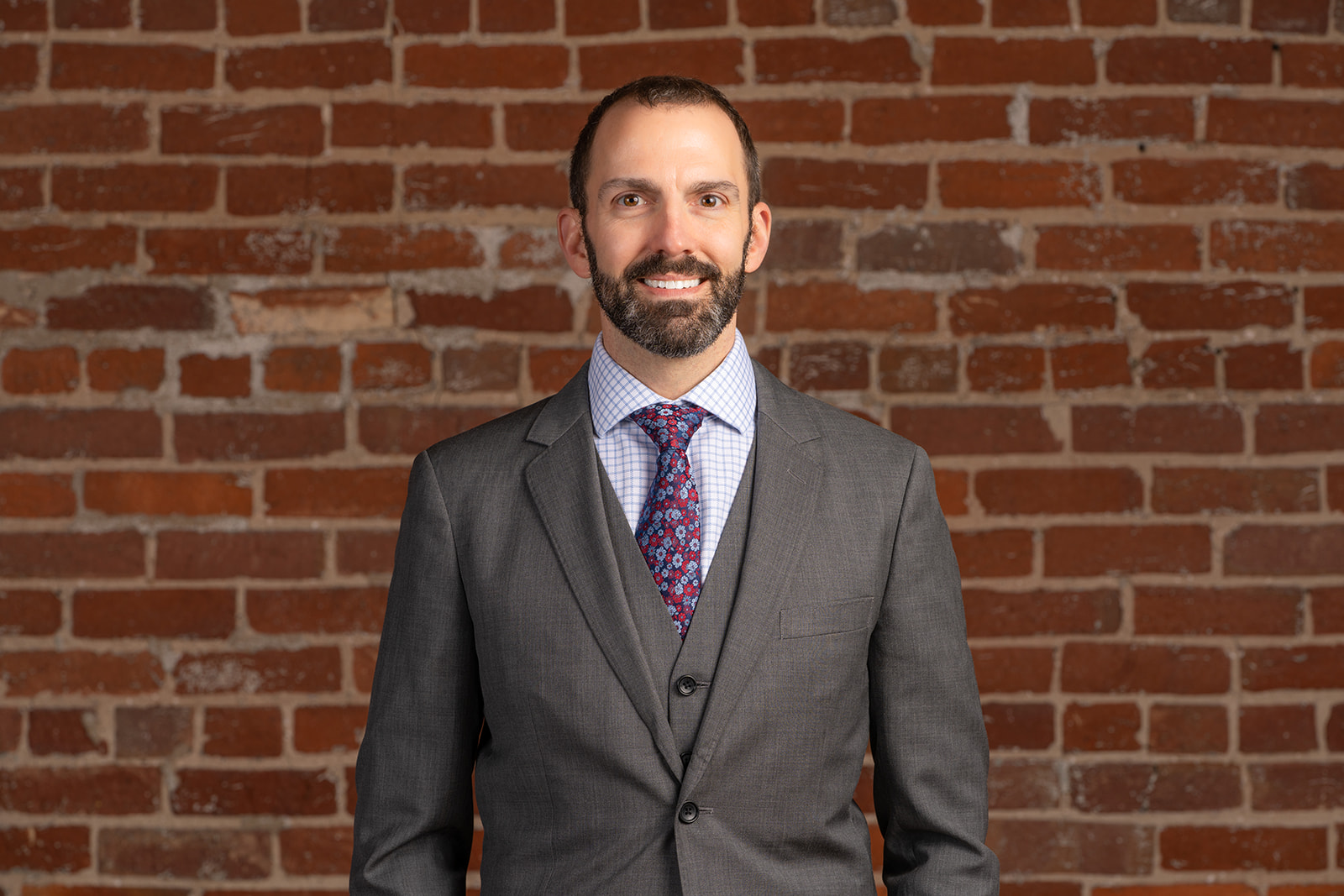 Dr. Christopher Toth in a suit with red brick background