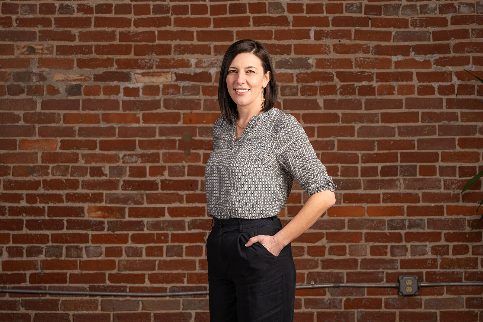 Team member Marija, standing in front of a red brick wall.