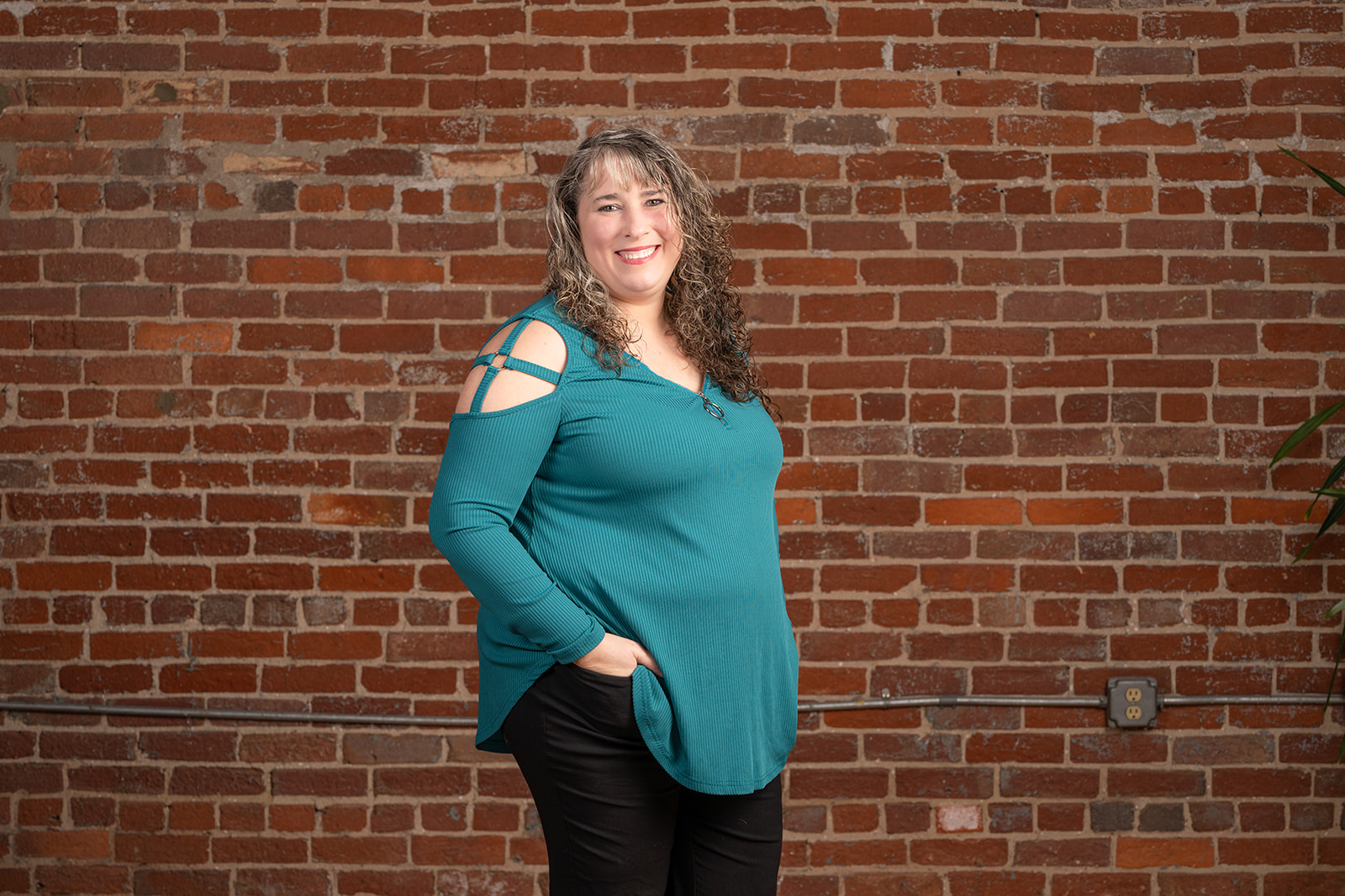 Team member Shelly, standing in front of a red brick wall.